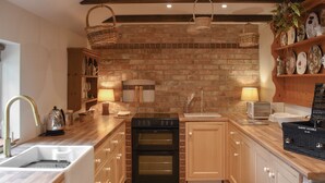 Una cocina con pared de ladrillo, armarios de madera, un lavabo, una estufa y un tostador.