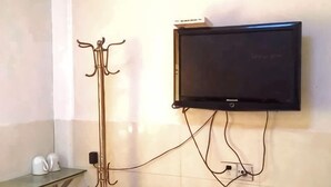 Televisor de pantalla plana penjat a la paret, amb cables visibles i un penjallabecs a l'esquerra.
