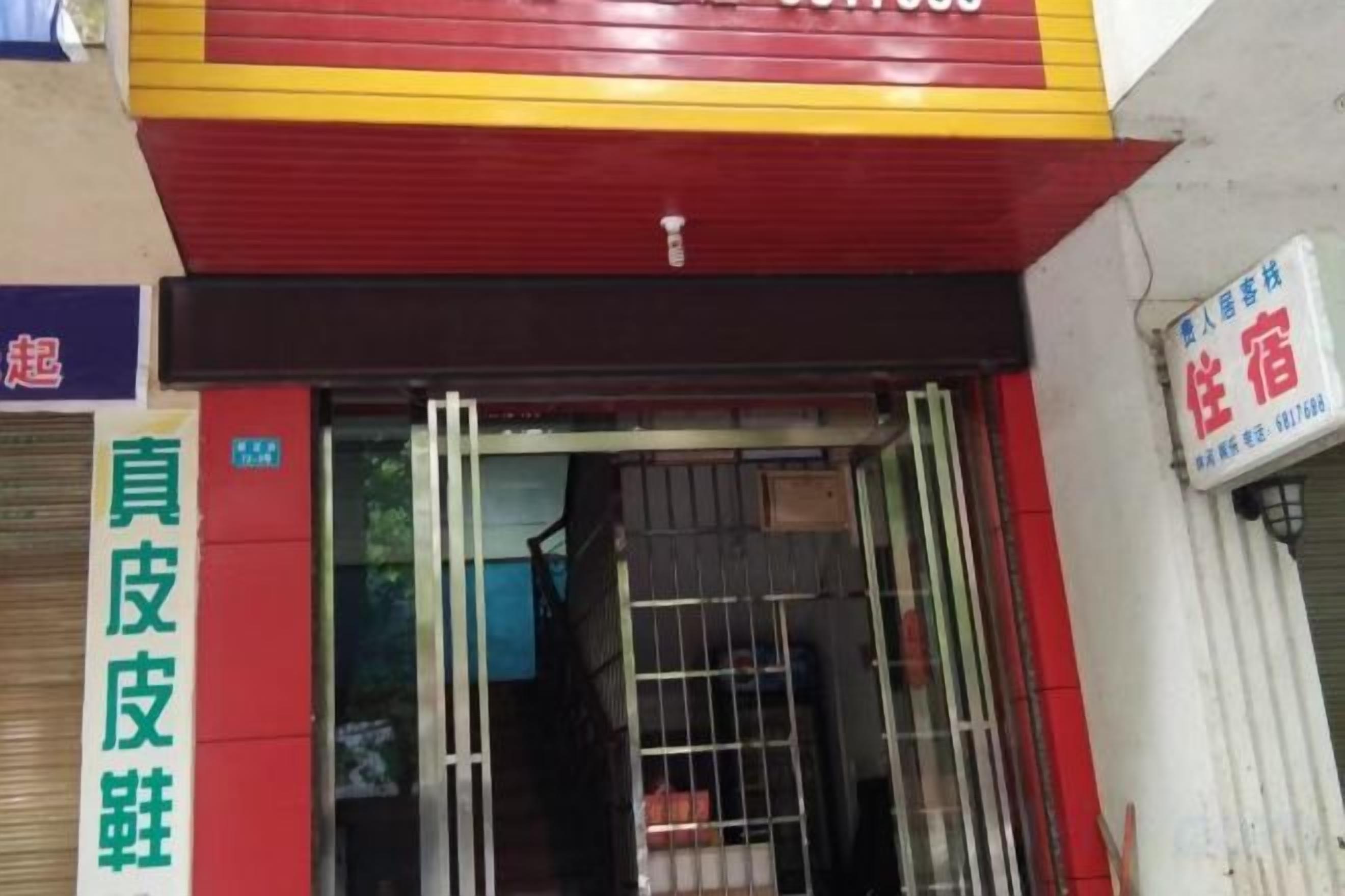 A hotel entrance with a red and yellow awning, a metal gate, and a sign indicating a room type.