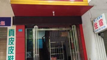 A hotel entrance with a red and yellow awning, a metal gate, and a sign indicating a room type.