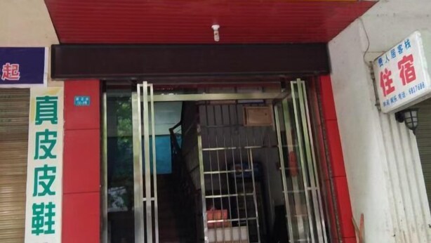 Entrada d'hotel amb una tenda vermella i groga, una porta ben visible i un senyal que indica una zona de servei d'habitacions.