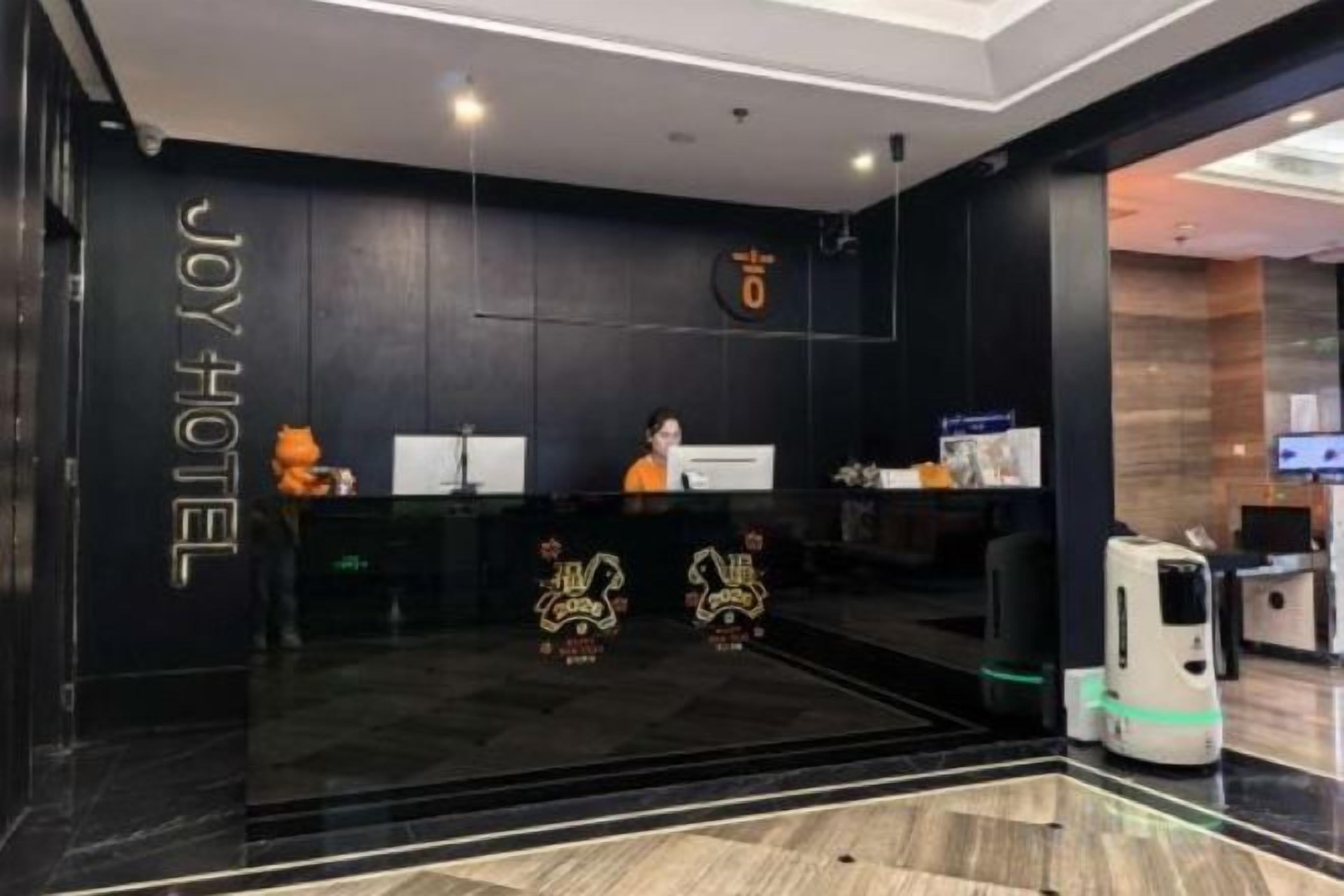 A hotel reception area with a dark interior, a reception desk, and a robotic vacuum cleaner.