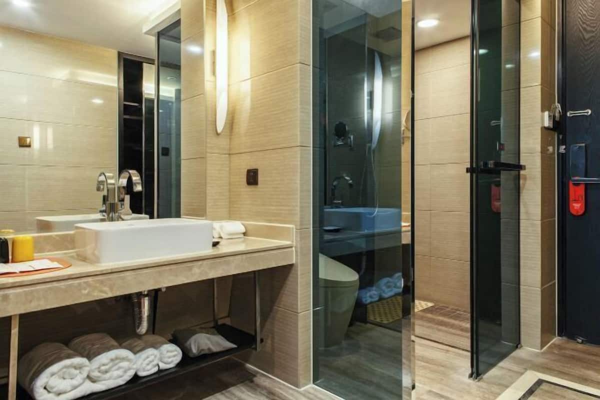A modern bathroom with a large mirror, a sink, and a glass-enclosed shower area.