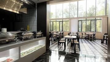 A restaurant with a buffet setup, large windows, and a tiled floor.
