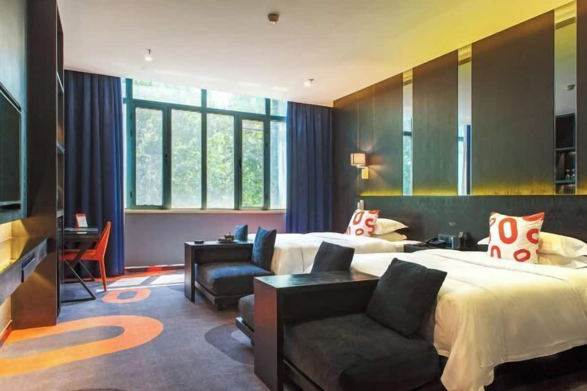 A hotel room with two beds, a desk, and a sofa.