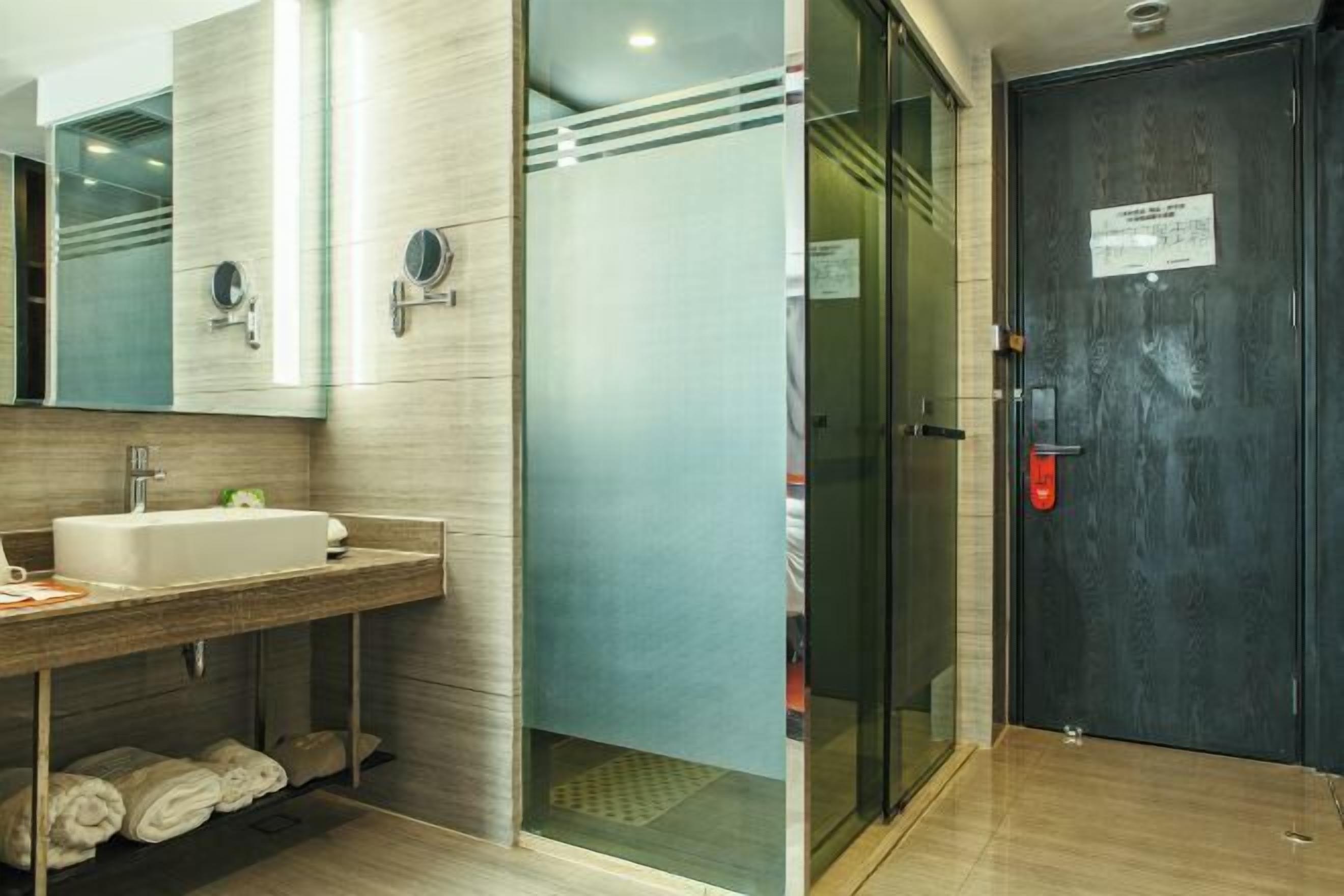 A modern bathroom with a sink, mirror, and glass shower enclosure.