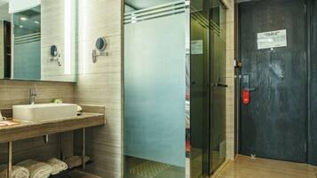 A modern bathroom with a sink, mirror, and glass shower enclosure.
