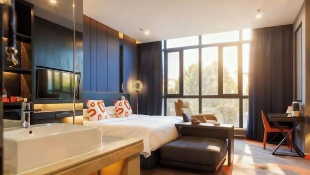 A modern hotel room with a large bed, a desk, a sofa, a TV, and a large window. - Jiyi Hotel (Yining Beijing Road Branch) (Yining City)