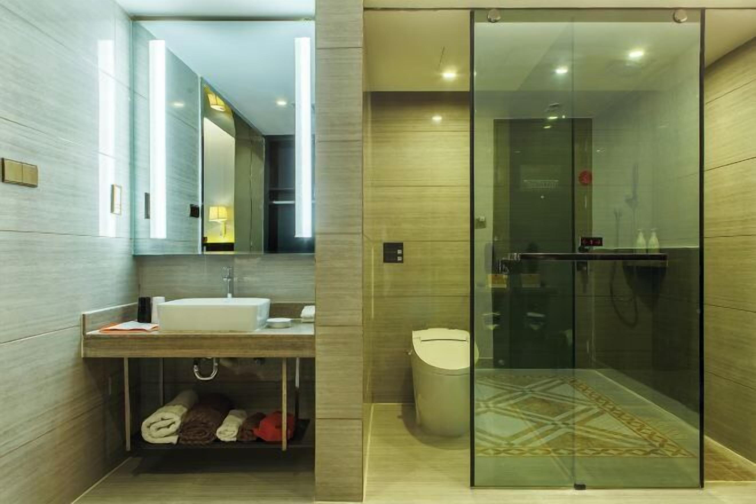 A modern bathroom with a glass-enclosed shower, a vanity with a sink, and a toilet.
