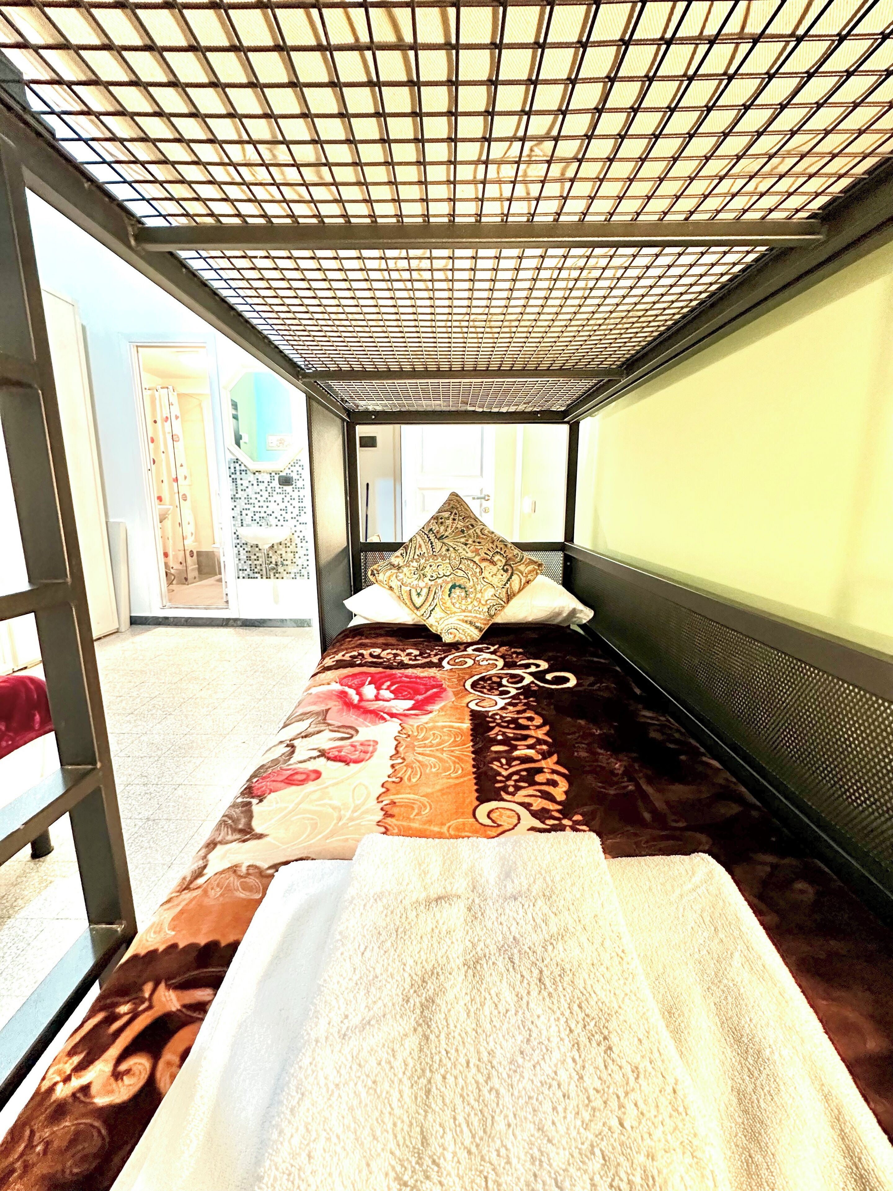 A room with a bed, a large window, and a view of the outside.