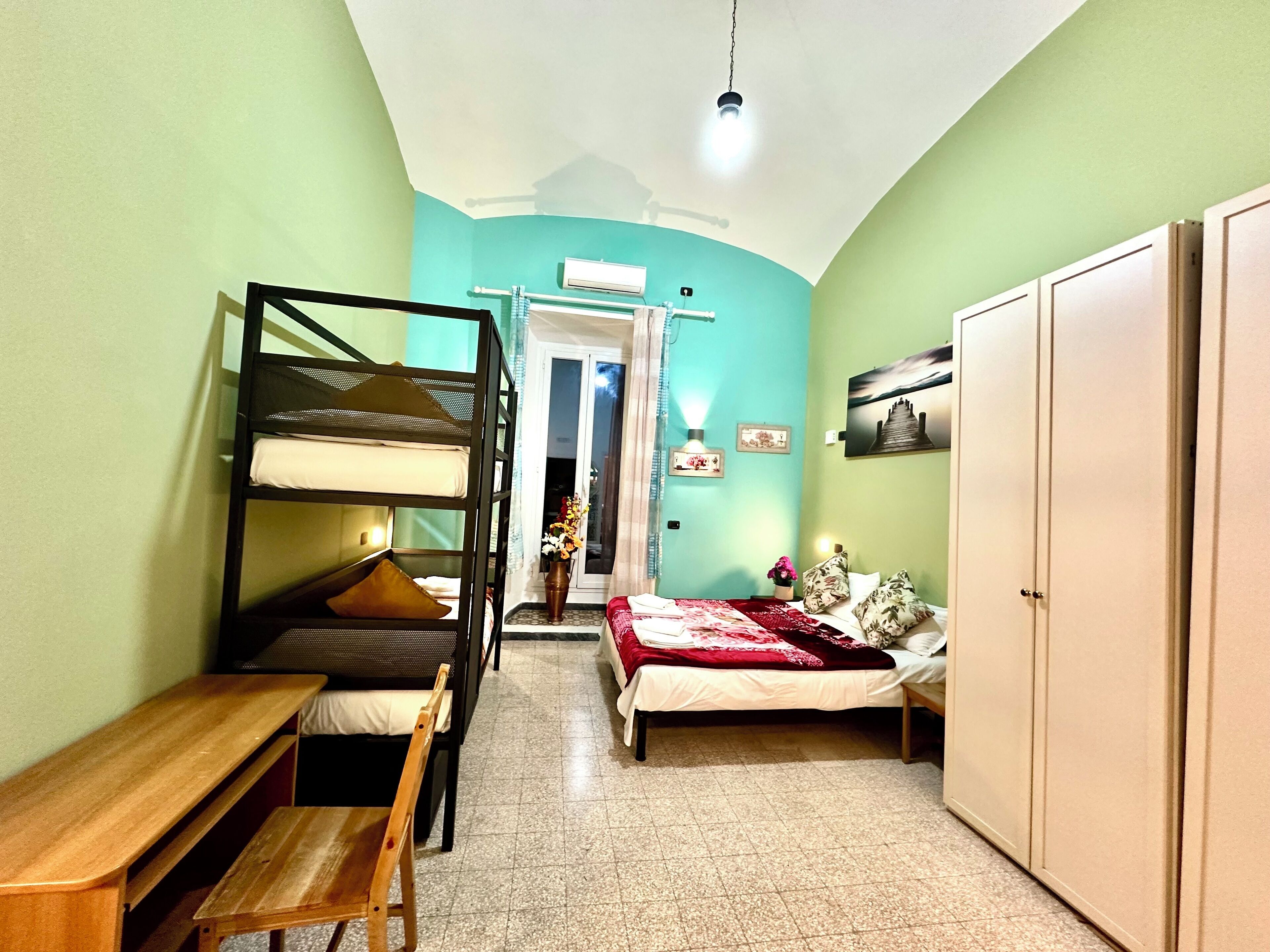 Habitació petita amb lliteres, un llit individual, una banca de fusta i un armari.