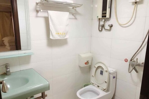 A bathroom with a toilet, a sink, a shower, and a towel hanging on a rack.