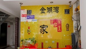 A reception area with a yellow wall, a red counter, and various signs and decorations. - Jinhuwan Hotel (Binhai)