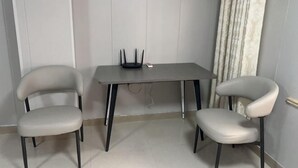 A small room with a grey table and two chairs, a white door, and a curtain. - Jinhuwan Hotel (Binhai)
