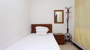 A small, neatly made room with a single bed, a wooden nightstand, a coat rack, and a mirror on the wall. - Jinhuwan Hotel (Binhai)