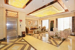 Un hall de hotel con mostrador de recepción, zona de estar y un ascensor.