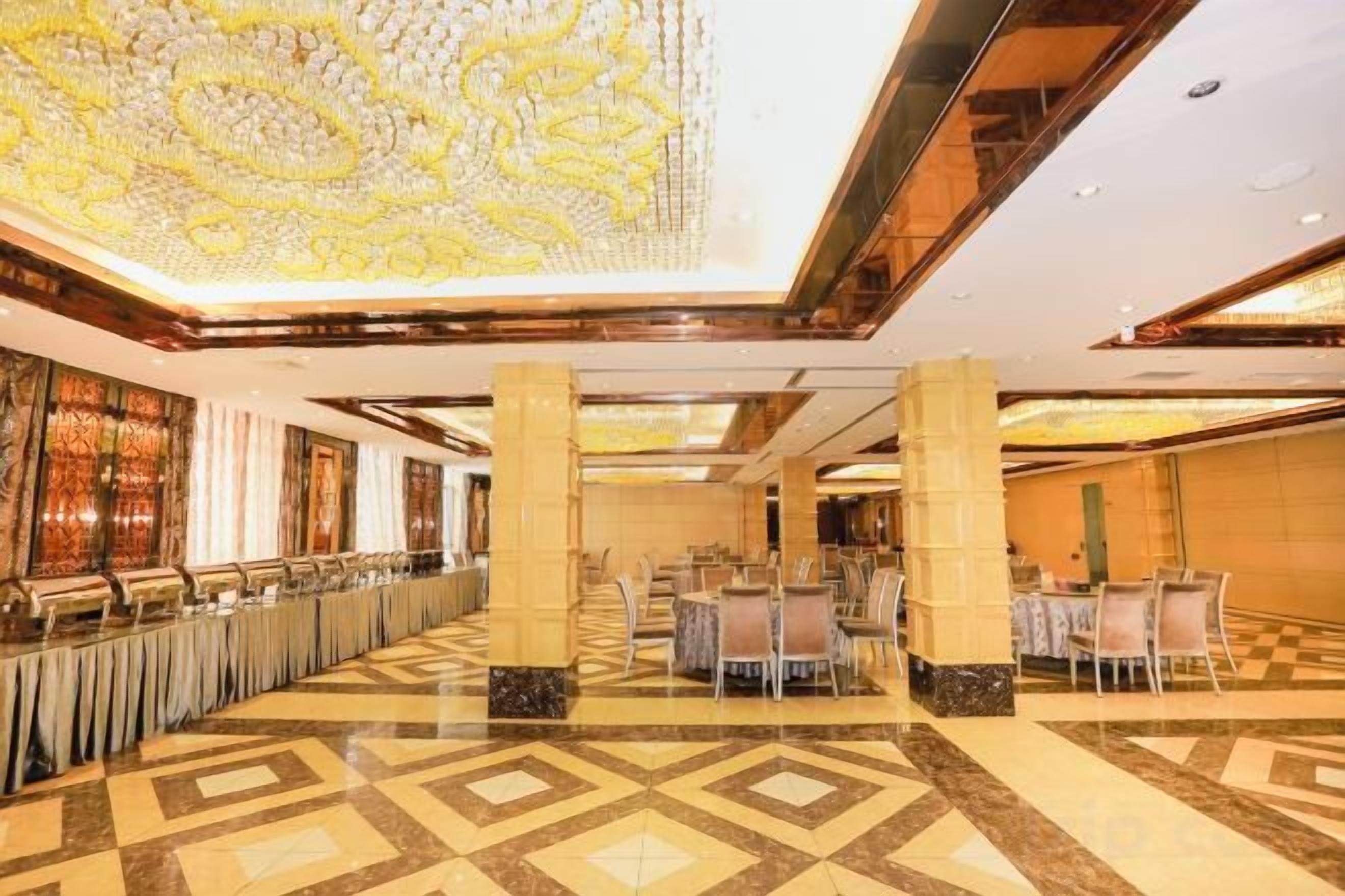 A spacious hotel lobby with a patterned floor, high ceilings, and a decorative ceiling design.