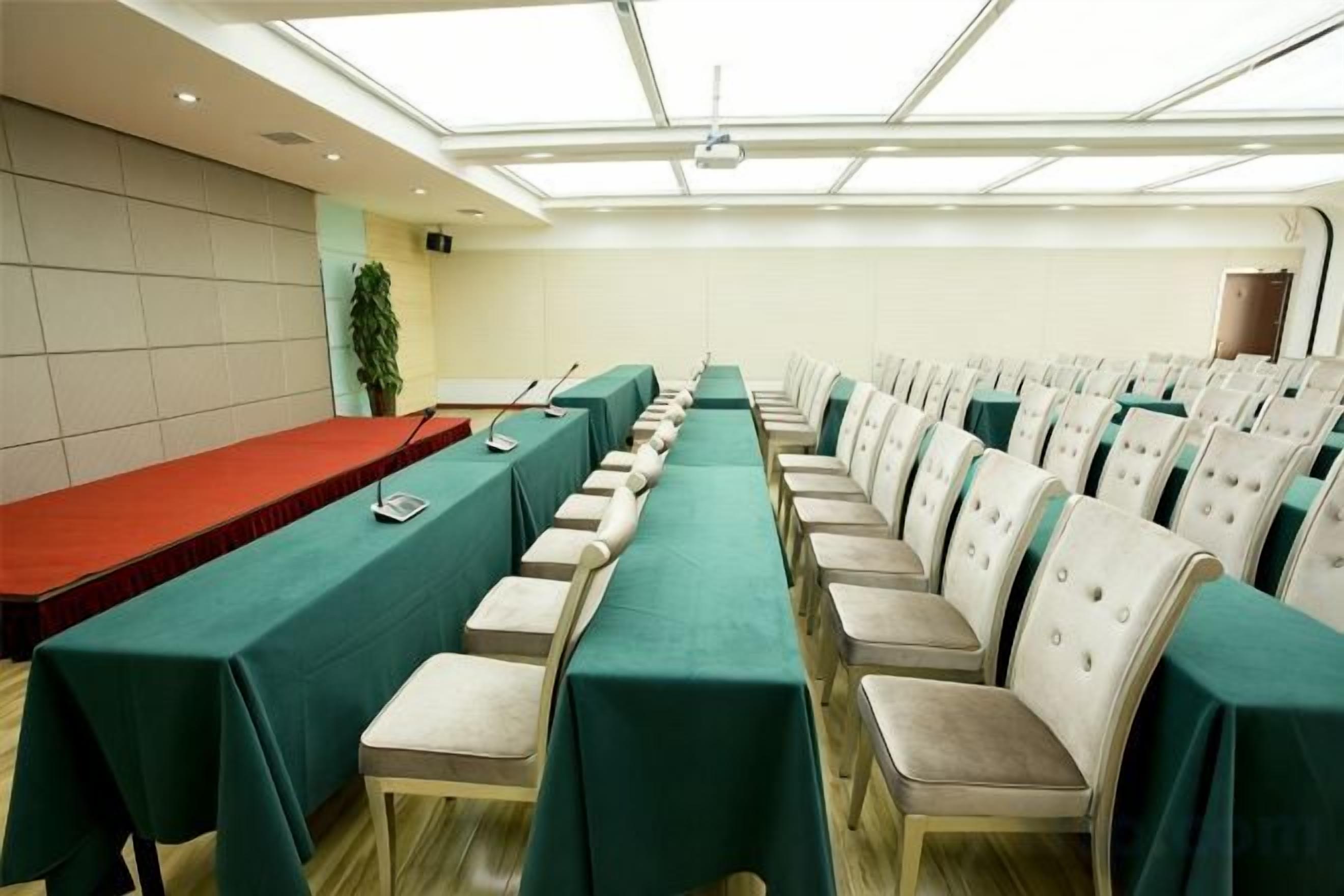 Un salón de conferencias con una larga mesa, sillas y un proyector.