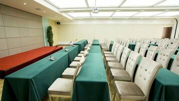 Un salón de conferencias con una larga mesa, sillas y un proyector.