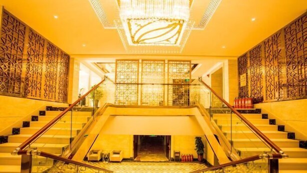 A grand staircase leading to a lobby with patterned walls and a chandelier.