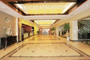 A hotel lobby with a long corridor, a reception desk, and a chandelier. - Xiaolajiao Hotel (Zhangye Jinzuo) (Zhangye)
