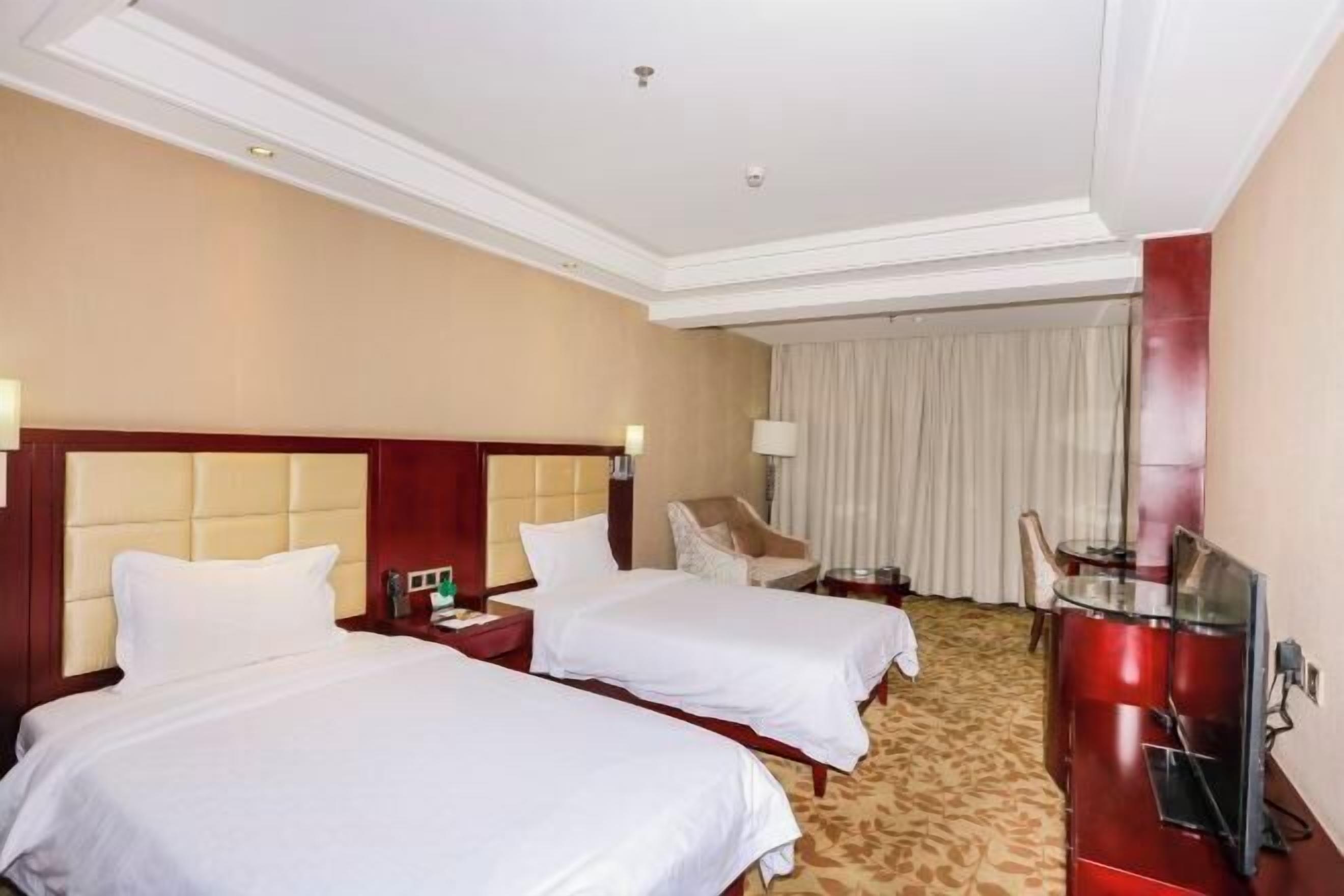 Une chambre d’hôtel avec deux lits, un bureau, une chaise et un téléviseur.