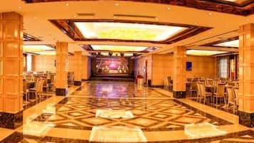 A spacious hotel lobby with a central stage, multiple seating areas, and a patterned floor.