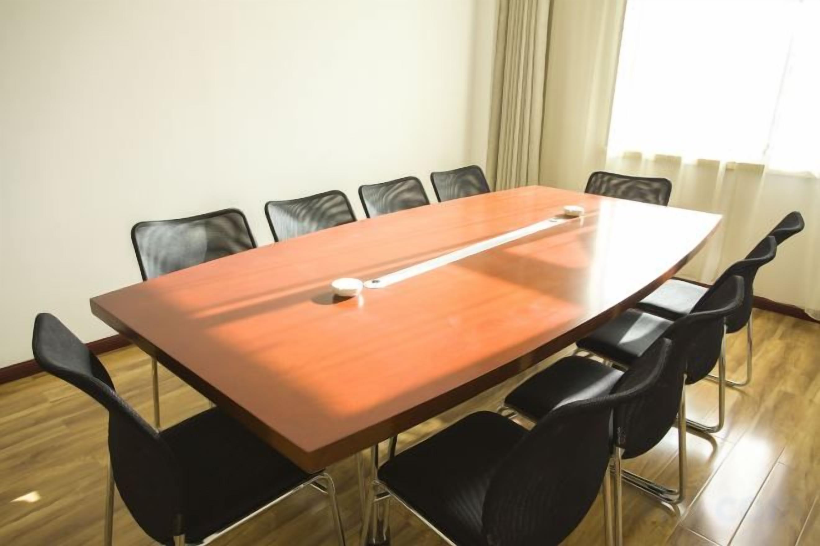 A conference room with a long table, six chairs, and a whiteboard.