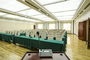 Un salón de conferencias con mesas dispuestas en filas, un atril y un amplio ventanal.
