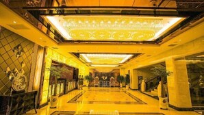 A spacious lobby with a large chandelier, polished floors, and a central seating area.