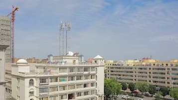 A multi-story building with balconies, a parking area, and a construction crane in the background.