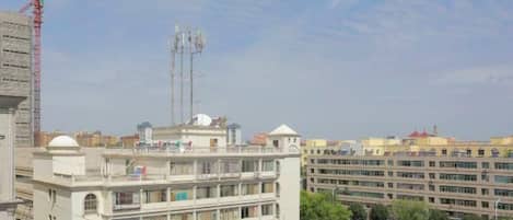 Un edificio de varios pisos con balcones, un estacionamiento y una grúa de construcción al fondo.