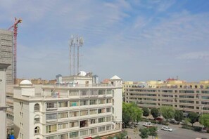 A multi-story building with balconies, a parking area, and a construction crane in the background. - Xiaolajiao Hotel (Zhangye Jinzuo) (Zhangye)