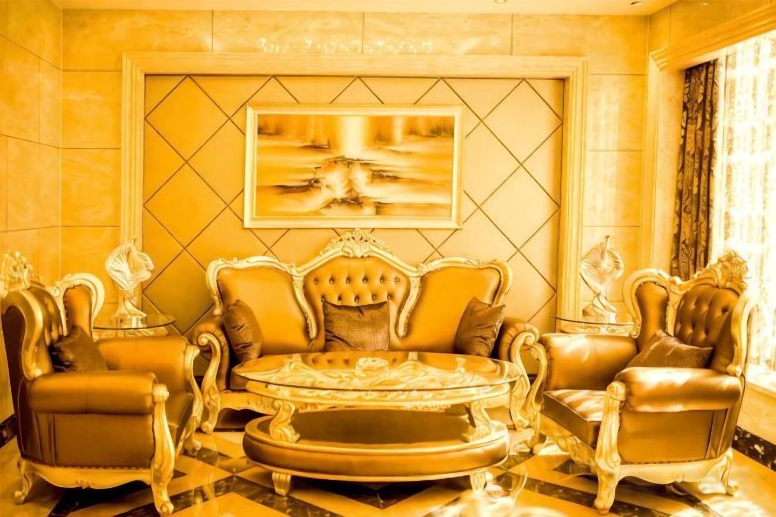 A luxurious room with a large, ornate sofa set, a round coffee table, and matching armchairs.