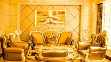 A luxurious room with a large, ornate sofa set, a round coffee table, and matching armchairs.