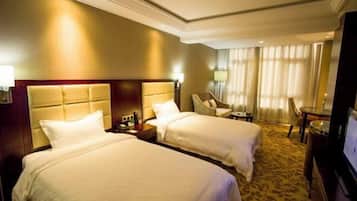 Ein Hotelzimmer mit zwei Betten, einem Fernseher, einem Schreibtisch und einem Stuhl.