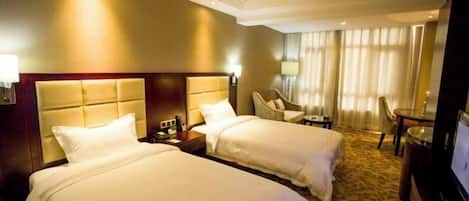 A hotel room with two beds, a television, a desk, and a chair.