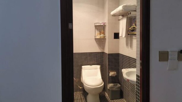 A small bathroom with a toilet, sink, and towel rack. - Chengdu Chongning Image Hotel (Chengdu)