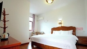 A bedroom with a wooden bed, a desk with a kettle, a chair, a window with curtains, and a wall-mounted air conditioner. - Huiyun Homestay, Yuli Ancient Town (Fuliang)
