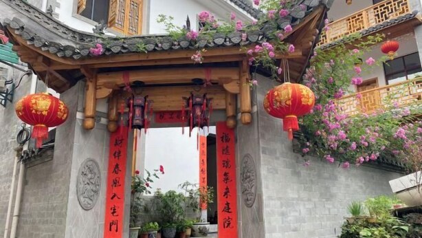 A traditional Chinese gate with red banners and hanging lanterns, leading to a courtyard with potted plants and a stone pathway. - Huiyun Homestay, Yuli Ancient Town (Fuliang)