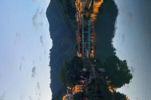 Un río que refleja un puente y edificios, rodeado de árboles.