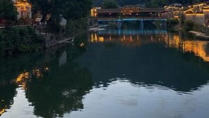 A serene riverside view with traditional architecture, a bridge, and a calm water body reflecting the buildings. - Huiyun Homestay, Yuli Ancient Town (Fuliang)