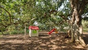Ein Spielplatz mit einer Rutsche und einem kleinen hausähnlichen Gebilde.
