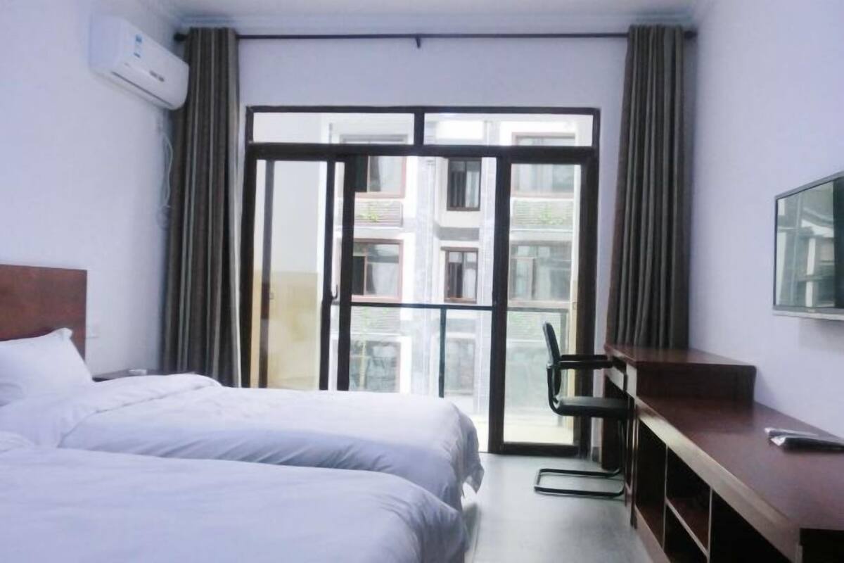 A hotel room with a bed, a desk, a chair, and a TV.