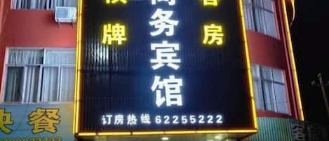 A hotel sign with Chinese characters, a phone number, and a website address.