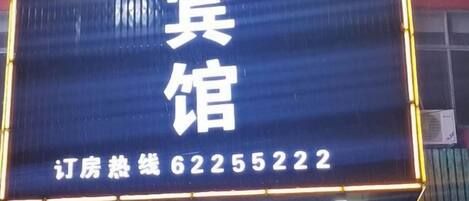 A digital signboard with hotel information and a contact number.
