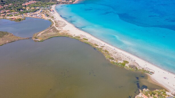 Luchtbeeld van een kustgebied met een strand, een klein meer en een brug die de twee verbindt.