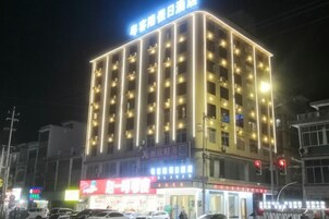 Un hotel de varios pisos con señalización iluminada y una zona comercial en la planta baja.