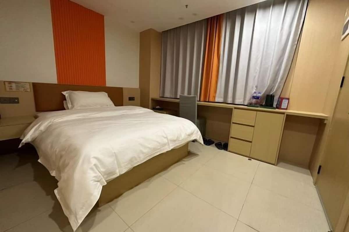 A hotel room with a bed, a desk, and a wardrobe.