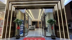A hotel entrance with a red carpet, glass doors, and potted plants. - Ganzhou Yuekelong Holiday Hotel (Ganzhou)